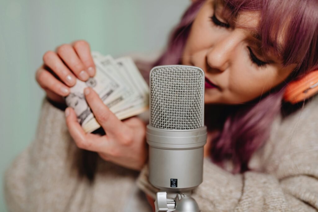 A young woman uses a microphone and money for an ASMR video indoors.